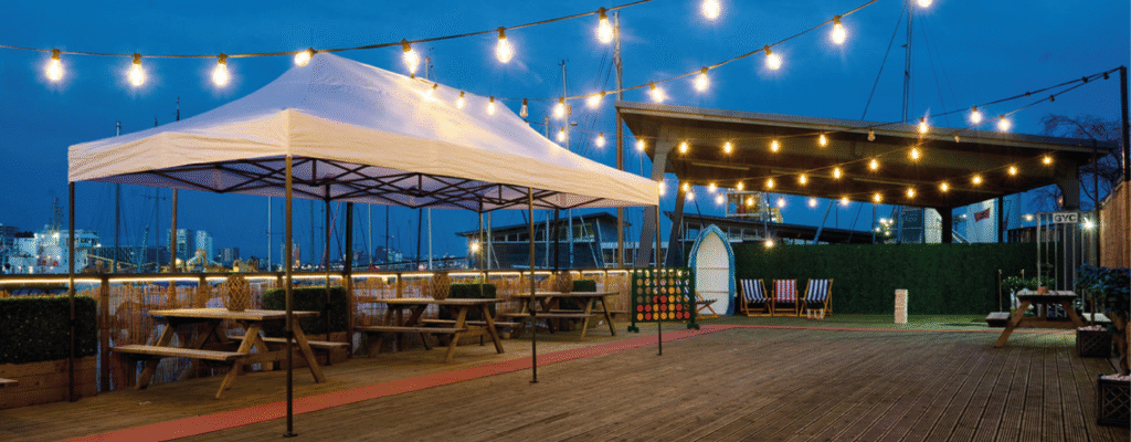 White gazebo with outdoor games and deck chairs at Greenwich Yacht Club