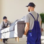Male,Movers,Team,Of,Moving,Service,Carrying,Heavy,Sofa,Together
